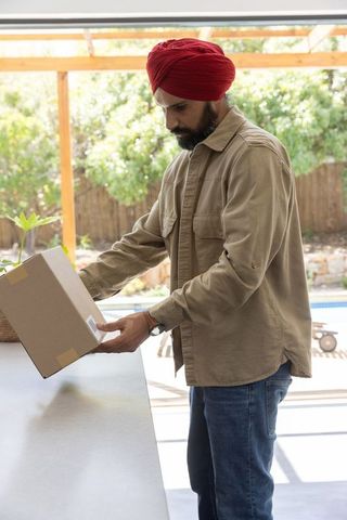 Man in red turban holding package near poolside patio