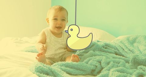 Cheerful Baby with Duck Illustration on Bed in Soft Light
