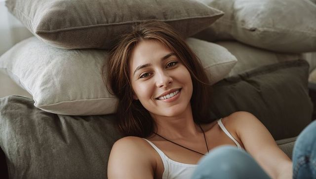 Smiling Woman Relaxing on Sofa With Cushions
