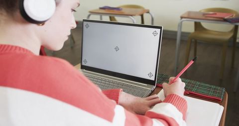Girl Studying with Laptop and Headphones in Classroom