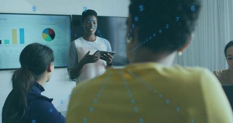 Diverse team collaborating in boardroom, presenter holding tablet presenting analytics