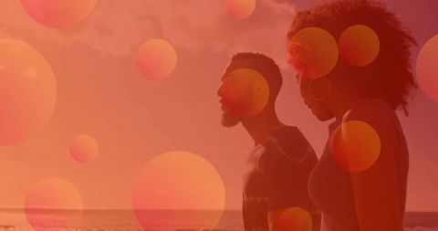 Silhouetted Couple Walking Along Beach with Warm Bokeh