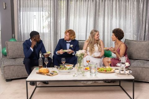 Elegant Wedding Party Sharing Food on Sofa with Wine