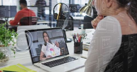 Woman watching laptop presentation in office with remote collaboration and data overlays
