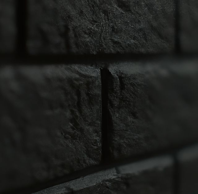 Dark textured brick wall in close-up with pronounced shadows, highlighting the deep textures and details. Ideal for use in backgrounds, architectural designs, dark-themed concepts, industrial presentations, and art projects requiring a rough, dramatic texture.