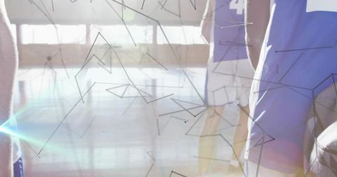 Basketball players standing in blue numbered jerseys on gym court with lens flare