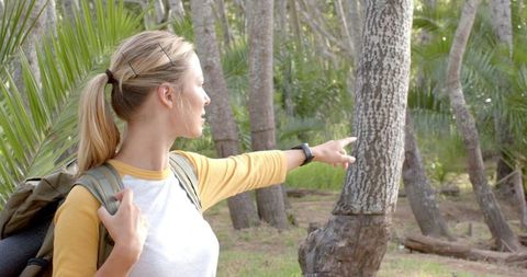 Young woman adventurer points at nature in scenic forest