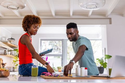 African american couple organizing medication and smoothies while planning wellness routine