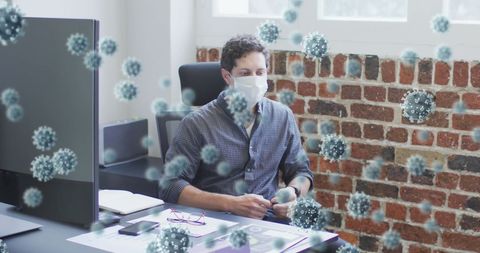 Man in office wearing mask surrounded by coronavirus cells