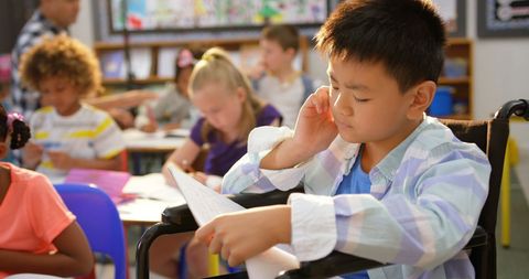 Focused Asian Boy in Wheelchair Studying in Classroom - Download Free Stock Images Pikwizard.com