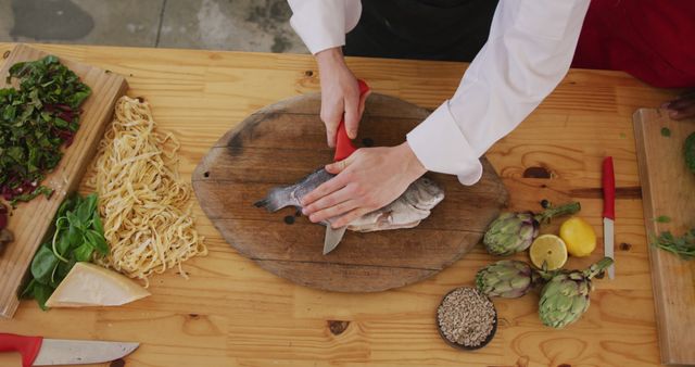 Hands of caucasian female cook slicing fish on cutting board in kitchen - Download Free Stock Photos Pikwizard.com