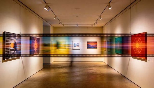 Translucent filmstrip sliding through contemporary gallery with vibrant motion blur