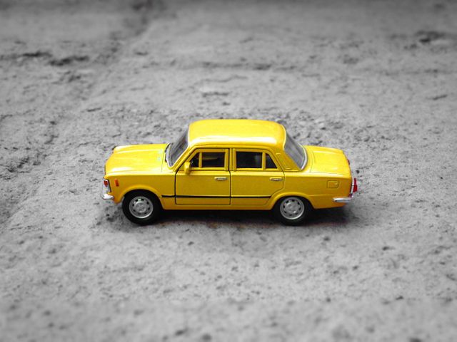 Yellow Toy Die Cast Sedan on Concrete Floor - Download Free Stock Photos Pikwizard.com