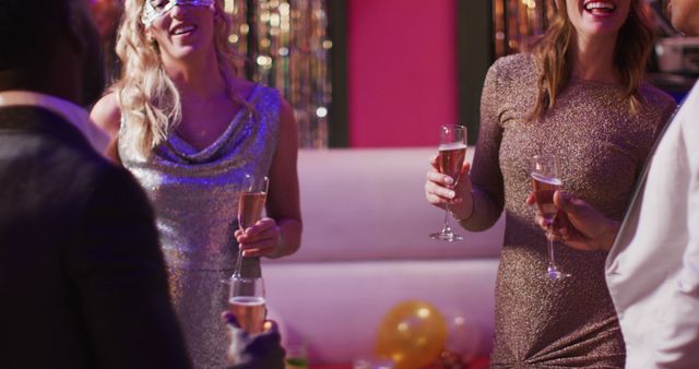 People celebrating in a nightclub with drinks in hand and wearing glittering dresses. Festive atmosphere with decorations in the background. Ideal for promoting parties, nightclubs, celebrations, and festive events.