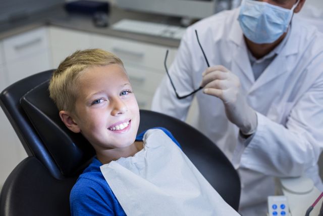 Smiling young patient sitting on dentist chair in dental clinic