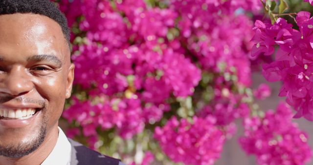 Smiling Man in Sunglit Outdoors with Vibrant Bougainvillea - Download Free Stock Images Pikwizard.com