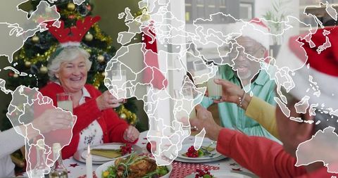 Seniors toasting holiday dinner with roasted turkey and christmas tree, world map overlay