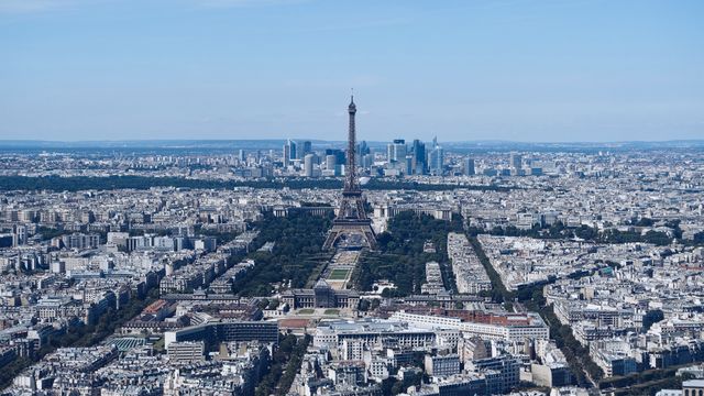 Panoramic aerial view capturing the beauty and density of Paris, featuring the iconic Eiffel Tower prominently in the center, with the modern skyscrapers of La Défense district in the background. Perfect for use in travel guides, tourism advertisements, or posters celebrating Paris. Could also be used in articles discussing architecture, urban development, or as a visual focal point for topics related to France and European travel.