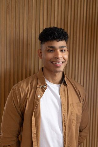 African american young man smiling against wood slat wall posing casual headshot lifestyle