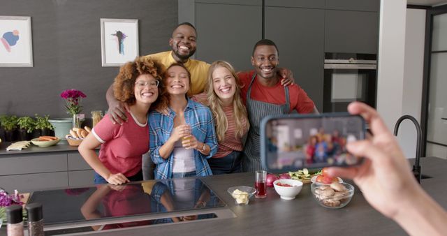 Happy diverse group of male and female taking picture with smartphone in kitchen. Friendship, togetherness, cooking, communication and celebration, unaltered.