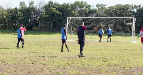 Diverse soccer team practicing drills on grassy outdoor field