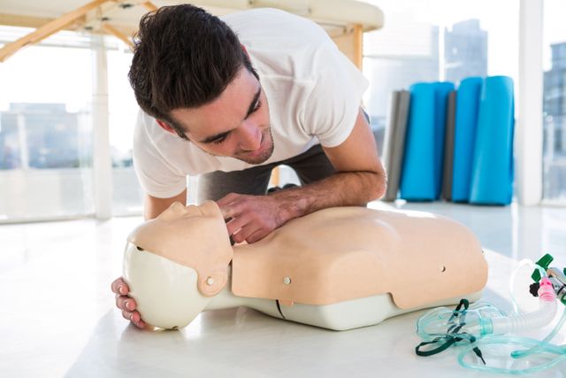 Paramedic practicing resuscitation on dummy in clinic