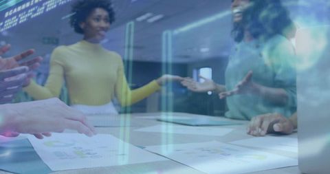 Collaborating team analyzing holographic data and printed charts over conference table