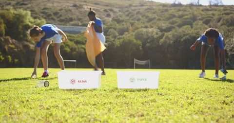 Diverse girls collecting recyclables on sports field