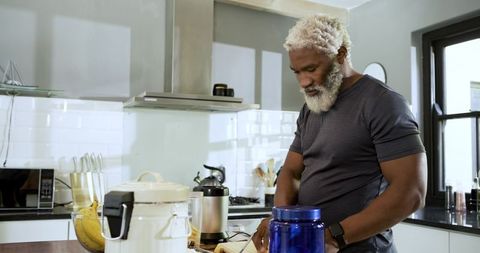 Senior man cooking at home, preparing ingredients in modern kitchen
