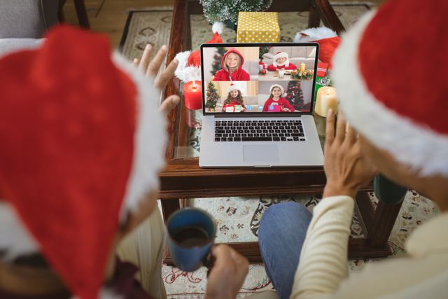Diverse couple with santa hats having video call with happy caucasian children. Christmas, celebration and digital composite image.