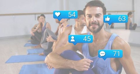Bearded man smiling in group yoga class with floating social media notification bubbles