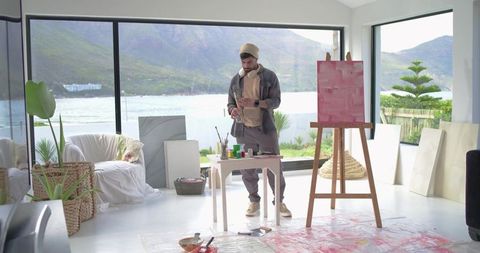 Indian artist painting in bright lakeside studio with abstract pink canvas