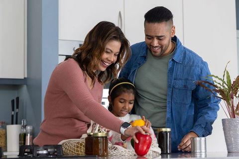 Family preparing fresh bell peppers together in modern kitchen for healthy meal prep