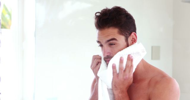 Young Man Drying Face with White Towel in Bright Bathroom - Download Free Stock Images Pikwizard.com