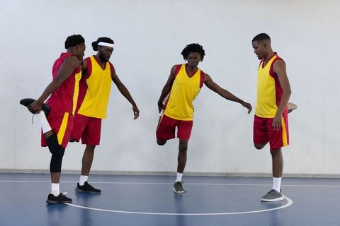 Male basketball players in yellow uniforms stretching on court