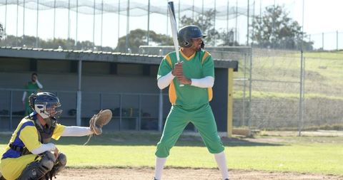 Batter preparing at home plate while catcher reaching for pitch during baseball game