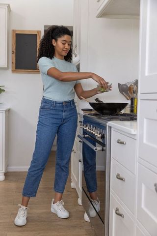 African American Woman Cooking with Wok in Minimalist Home Kitchen