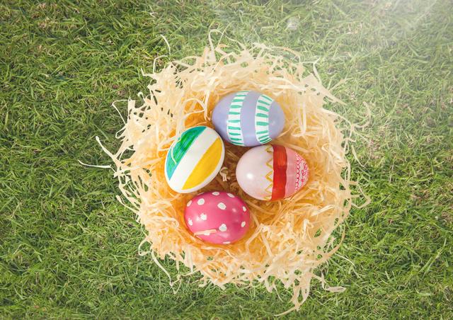 Hand-painted Easter eggs placed carefully in a straw nest situated on green grass make for an inviting and festive display, perfect for promoting Easter events, spring festivals, creative DIY projects, or seasonal greetings and decorations. Ideal for posters, social media content, and promotional materials during Easter celebrations.