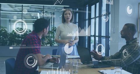 Asian woman leading data-driven team meeting with laptops and analytics overlays