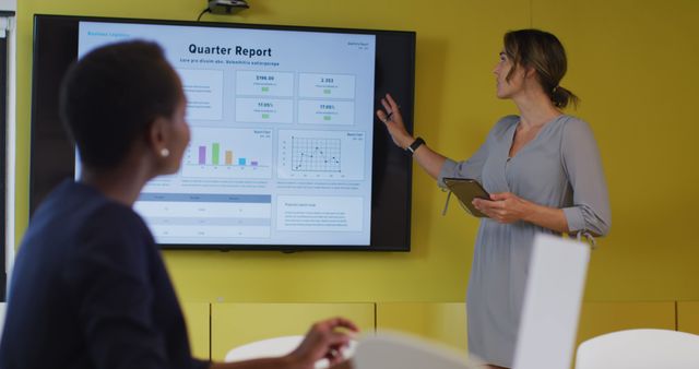 Businesswoman presenting a detailed quarterly report to colleagues in a modern office setting. Useful for illustrating business meetings, corporate presentations, teamwork, and business analytics.