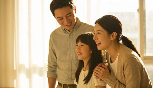 Smiling parents and daughter enjoying warm sunlit morning at home, family bonding