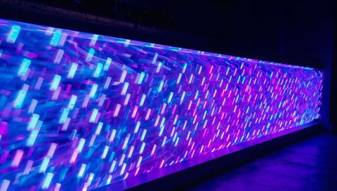 Pulsing neon led wall producing diagonal cyan blue magenta light streaks in dark interior