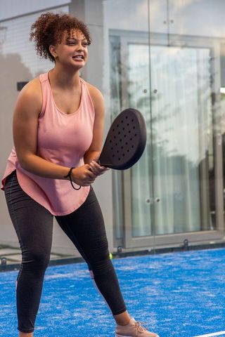 African american woman returning pickleball shot with black paddle on blue court