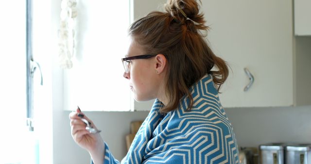 Woman in Kitchen Wrapped in Blue Patterned Blanket Drinking From Spoon - Download Free Stock Images Pikwizard.com