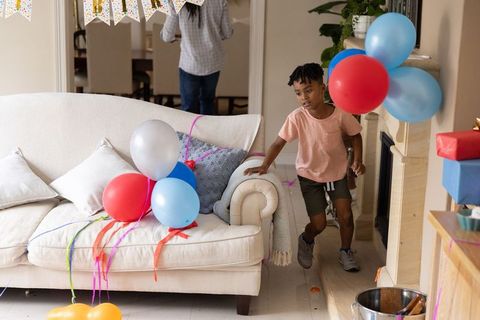 Young boy exploring living room during colorful birthday celebration with balloons