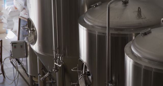 Modern, stainless steel brewing equipment seen in an industrial brewery setting. Useful for illustrating advancements in brewing technology and manufacturing processes. Ideal for articles, advertisements, or visuals related to beer production, brewery tours, and the science of fermentation.