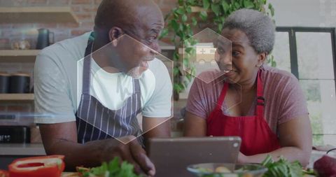 Lively elderly couple prepares salad in modern kitchen