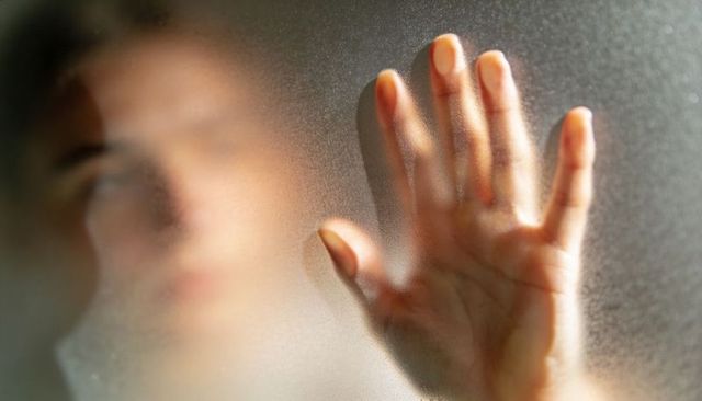 Pressing Hand Against Frosted Glass, Blurred Silhouette, Warm Backlight, Emotional Closeup