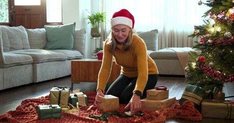 Senior Woman Preparing Gifts under Christmas Tree at Home
