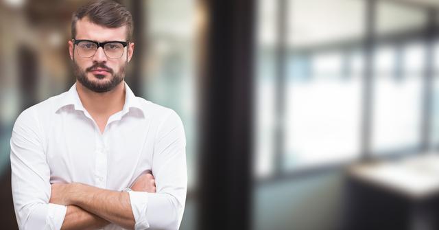 Confident young businessman standing with arms crossed wearing glasses, white shirt, and sporting a serious expression. Ideal for corporate, business, or professional themes. Can be used in business presentations, corporate websites, profiles, and advertisements emphasizing professionalism and confidence.